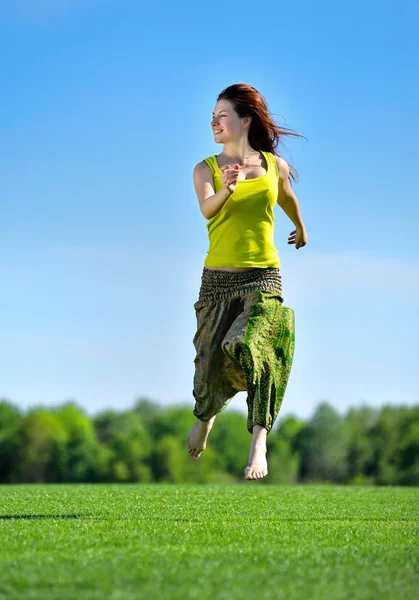 Jeune femme courant sur une prairie verte — Photo