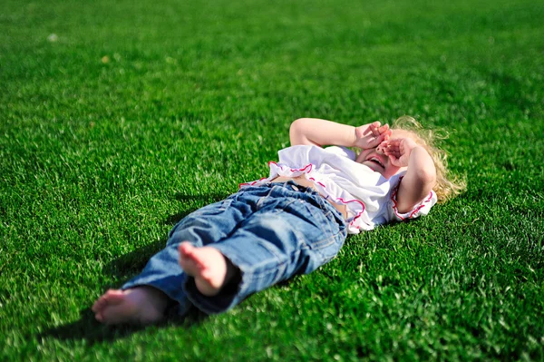 Menina do bebê deitado na grama verde no parque — Fotografia de Stock