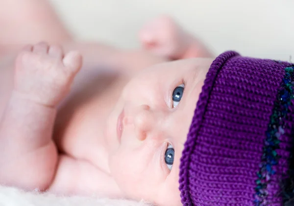 Menina recém-nascida deitada em um chapéu lilás — Fotografia de Stock