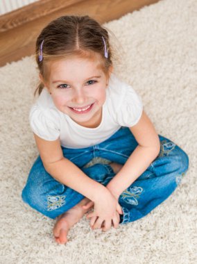 Küçük kız yerde oturuyor.