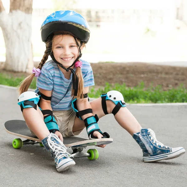 Μικρό κορίτσι που κάθεται σε ένα skateboard — 图库照片