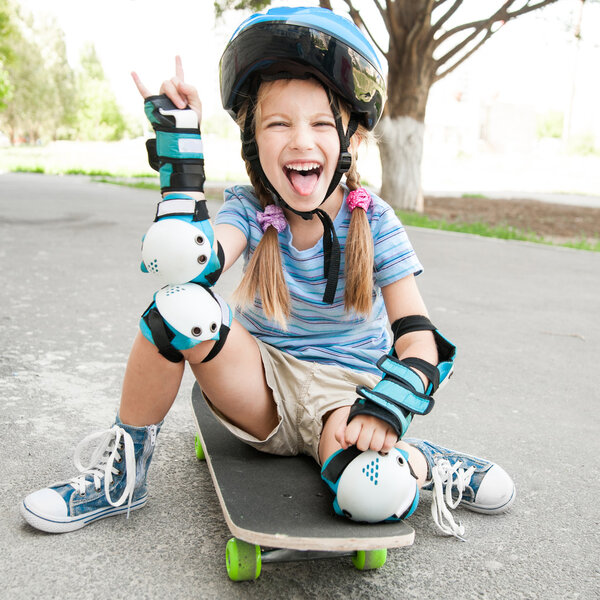Маленькая девочка сидит на скейтборде
