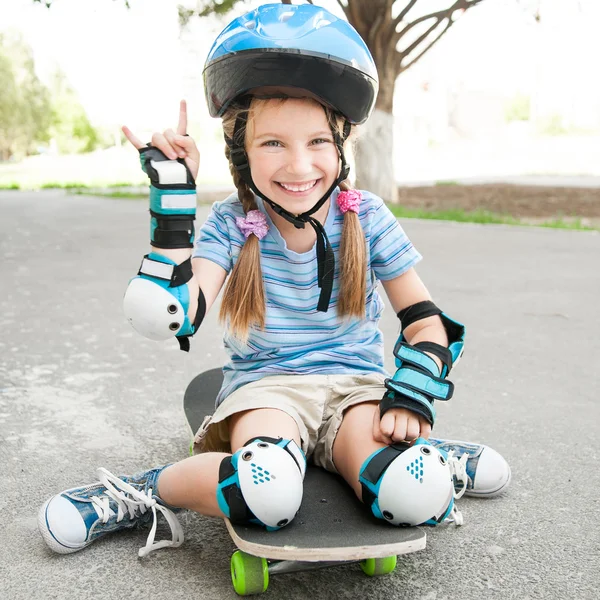 스케이트 보드에 앉아 어린 소녀 — 스톡 사진