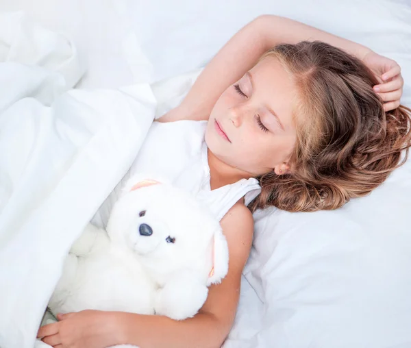 Menina na cama com ursinho de pelúcia — Fotografia de Stock