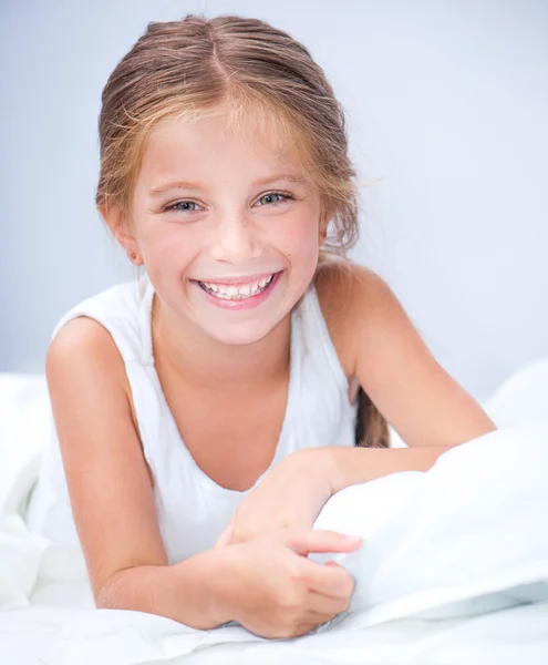 Petite fille souriante dans un lit Photos De Stock Libres De Droits