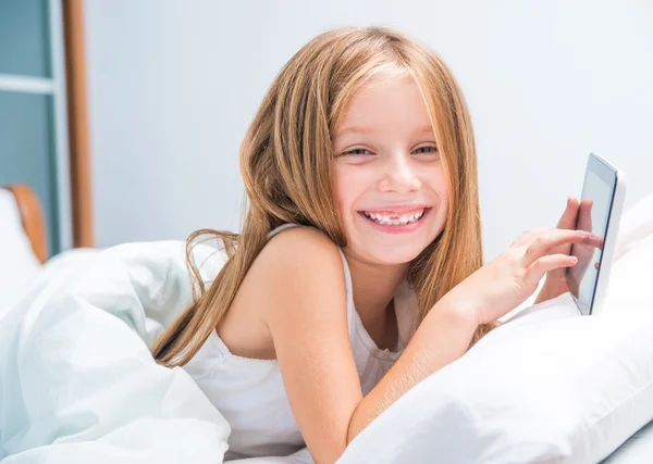 Scolaretta con tablet a letto a — Foto Stock