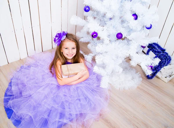 Petite fille avec un cadeau près de l'arbre de Noël — Photo