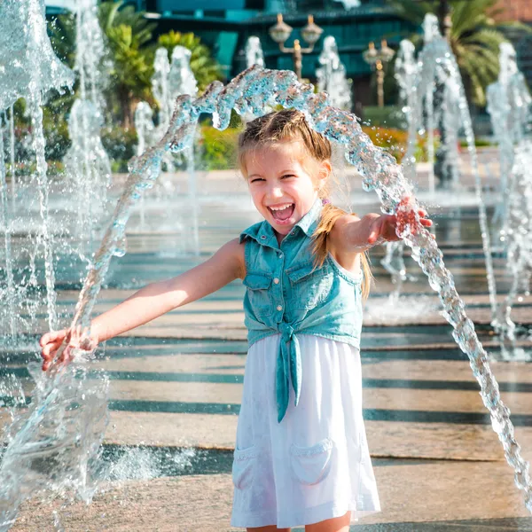 Kleines Mädchen spritzt einen Springbrunnen — Stockfoto