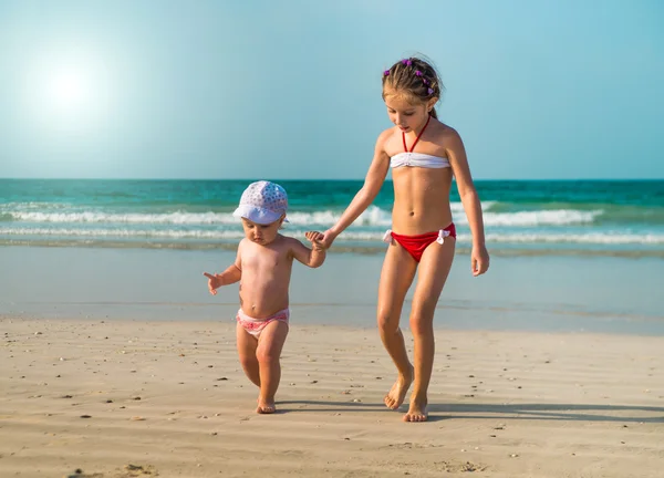 Little sisters walking along the beach — Stock Photo, Image