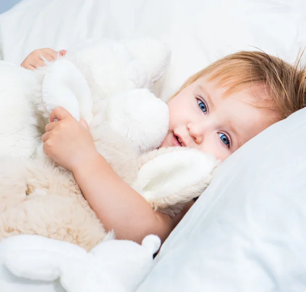 Μωρό με ένα παιχνίδια στο λευκό κρεβάτι — Φωτογραφία Αρχείου