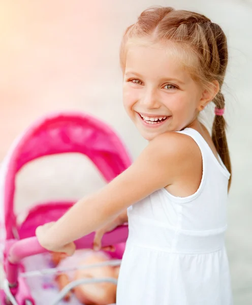 Bambina con carrozzina giocattolo — Foto Stock