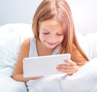 colegiala con tableta en cama en