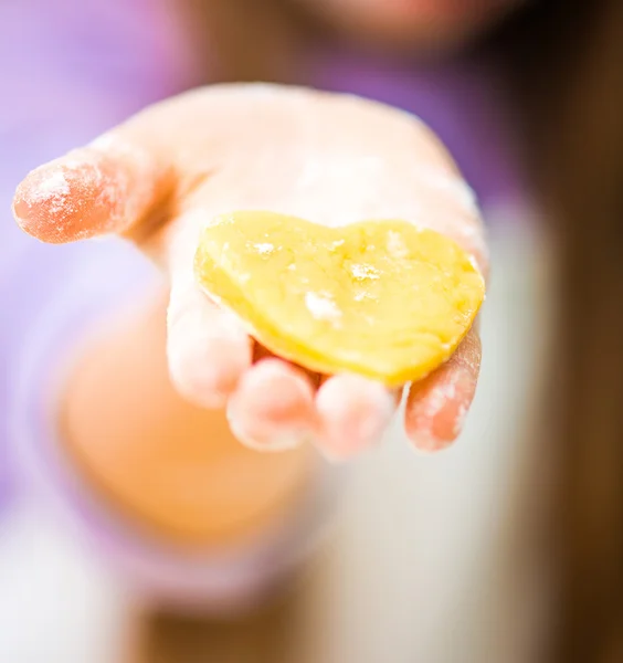 Little girl holding a heart-shaped dough — Stock Photo, Image