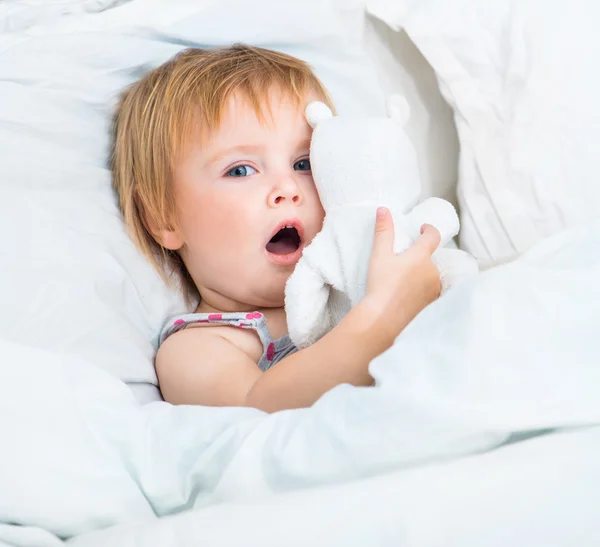 Baby met een speelgoed in witte bed — Stockfoto
