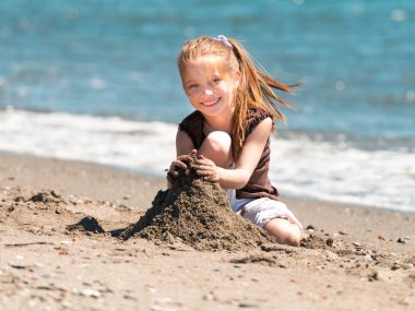 Kumsalda oynayan tatlı küçük kız.