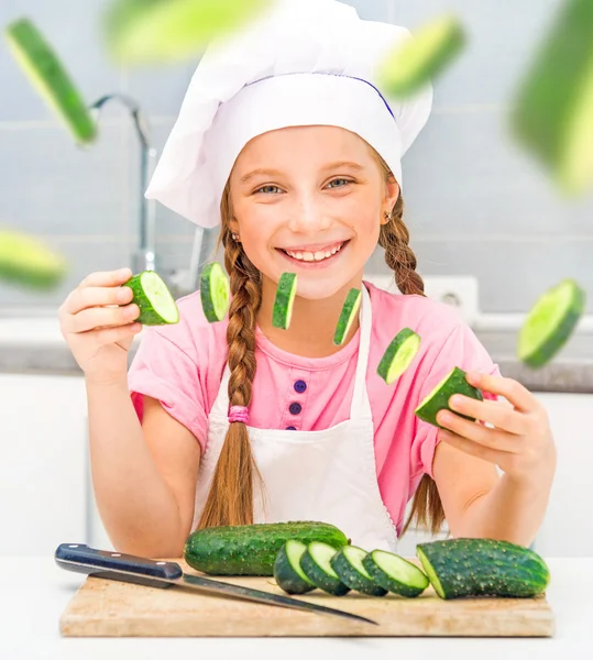 Girl cuts cucumbers in kitchen — Stock Photo, Image