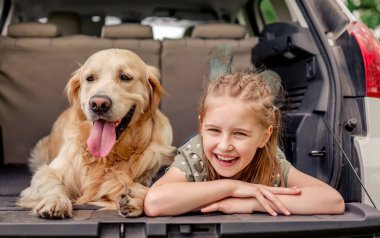 Arabasında golden retriever köpeği olan genç bir kız.