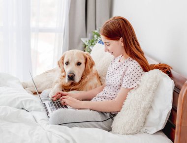 Dizüstü bilgisayarı ve golden retriever köpeği olan kız.