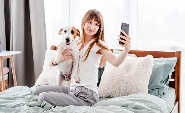 Menina com cão e smartphone na cama — Fotografia de Stock