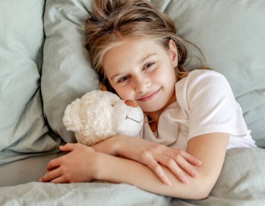 Yatağında oyuncak ayıyla çocuk kız