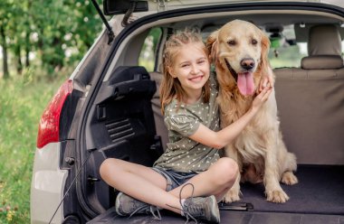 Arabasında golden retriever köpeği olan genç bir kız.