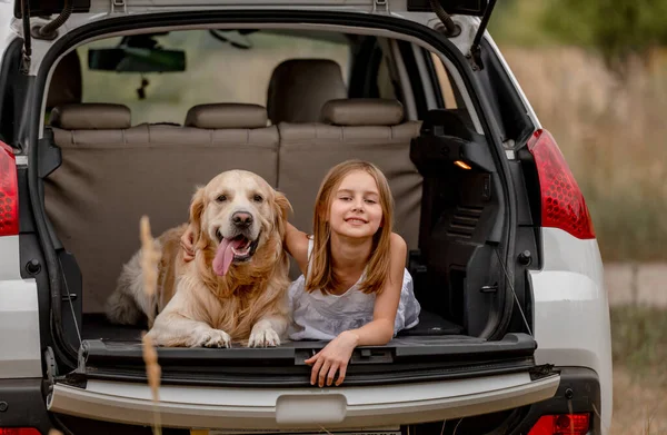 Nastolatka dziewczyna z golden retriever pies w samochód bagażnik — Zdjęcie stockowe
