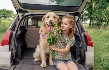 Arabasında golden retriever köpeği olan genç bir kız.