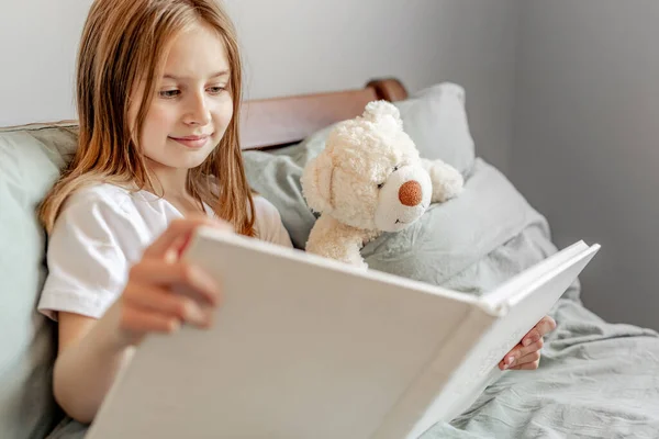 Menina com ursinho de pelúcia brinquedo na cama — Fotografia de Stock