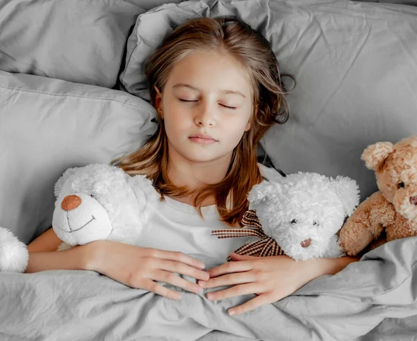 Menina com ursinho de pelúcia brinquedo na cama — Fotografia de Stock