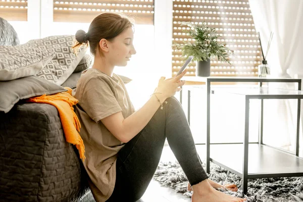 Menina com smartphone em casa — Fotografia de Stock