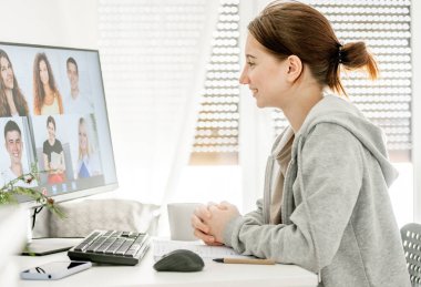 Sınıf arkadaşlarıyla video bağlantısı üzerinden uzaktan eğitim kursunda bir kız. Koronavirüs salgınında evde bilgisayarla gençlerin e-öğrenimi