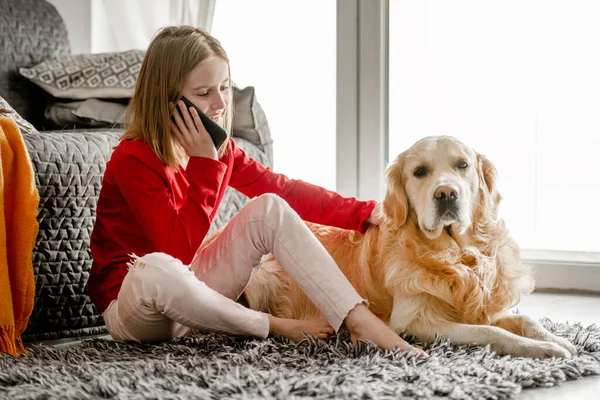 소녀는 바닥에 리트리버 앉아서 스마트폰으로 이야기를 기사보기 강아지가 핸드폰으로 통화하는 — 스톡 사진