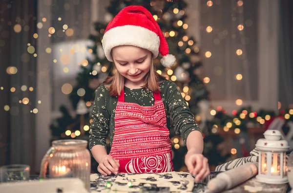 크리스마스 배경에 모자를 쿠키를 자르는 소녀의 — 스톡 사진
