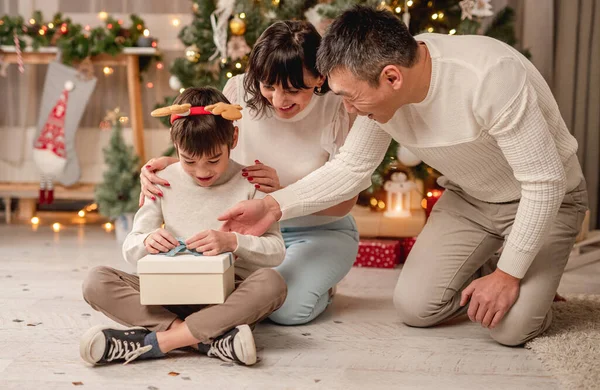 Sonriente Niño Unboxing Regalo Navidad Mientras Está Sentado Lado Padres —  Fotos de Stock