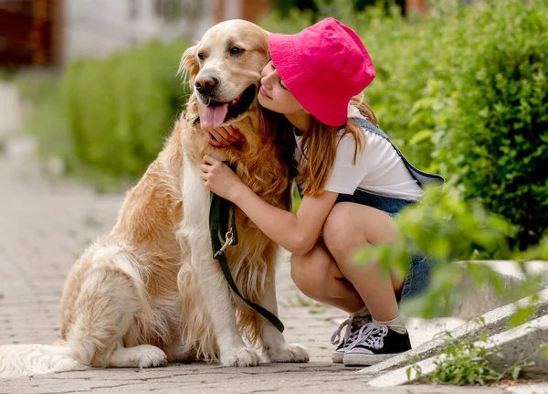 Preteen Girl Wearing Hat Hugging Golden Retriever Dog Sitting Outdoors — Stock Fotó