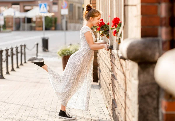Schöne Mädchen Langen Kleid Schnüffelt Rote Blumen Auf Der Straße — Stockfoto