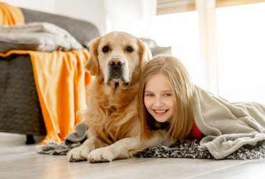 Neşeli kız Golden Retriever köpeğiyle ekose altında yatıyor. Saf köpek labrador 'u olan mutlu ergen kız yerde vakit geçiriyor..
