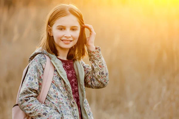 10代の女の子の子供がカメラを見て 現場で驚くべき日没の光の中で笑っています 美しい女性の子供の肖像画 — ストック写真