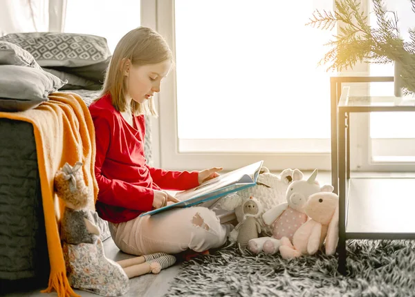 Adolescente Leyendo Libro Sentado Cerca Sofá Con Tpys Niño Descansando —  Fotos de Stock