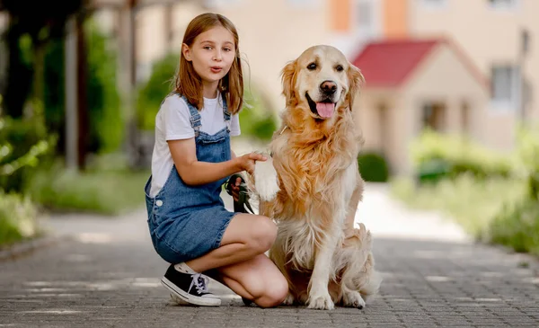 Preteen Girl Wearing Hat Hugging Golden Retriever Dog Sitting Outdoors — Stockfoto