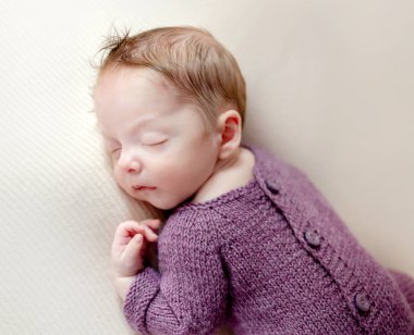 Newborn baby boy wearing knitted pants lying on knitted pillow. Cute infant child kid istudio photoshoot