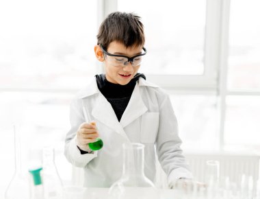 İlköğretim fen dersinde koruma gözlüğü takan öğrenci kimya deneyi yapıyor. Laboratuvarda ekipman tüplü gözbebeği.