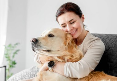 Golden Retriever köpeğini kucaklayan ve gülümseyen bir kız. Aşkla köpek besleyen genç kadın.
