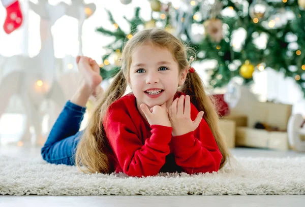 크리스마스 소녀는 카펫에 장식된 나무와 선물들로 카메라를 바라본다 휴일에 — 스톡 사진