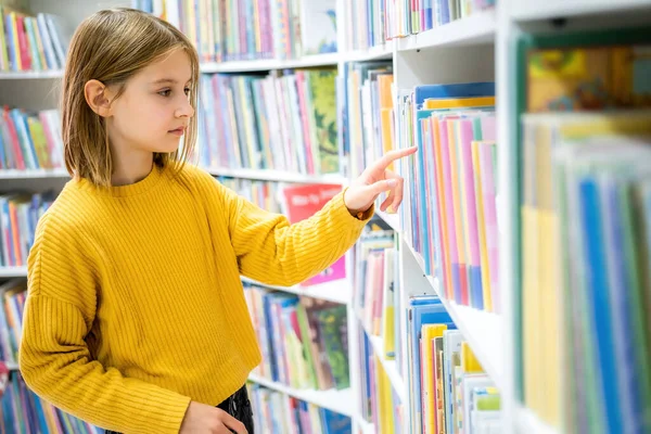 学校図書館で本を選ぶ女子高生 読書のための文学を選ぶスマートな女の子 書店の棚の本 本から学ぶ 学校教育 毎日の読書の利点 — ストック写真