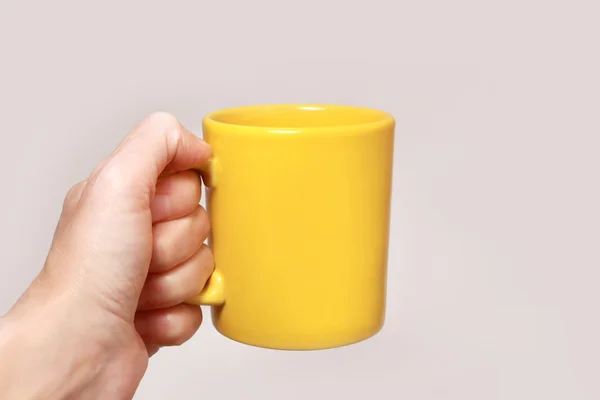 Tasse jaune tenant la main — Photo