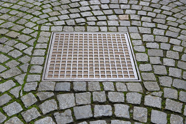 Straatstenen met metalen mangat — Stockfoto