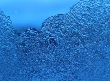 Camın üzerinde buz olan mavi arkaplan, doğal dokuyu yakın plan.