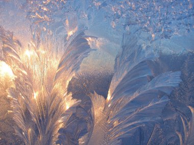 Beautiful ice pattern and sunlight close up on window glass early in the morning, natural winter background clipart