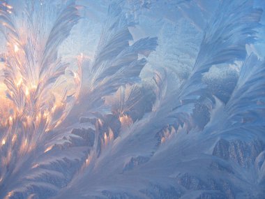 Beautiful ice pattern and sunlight close up on window glass early in the morning, natural winter background clipart